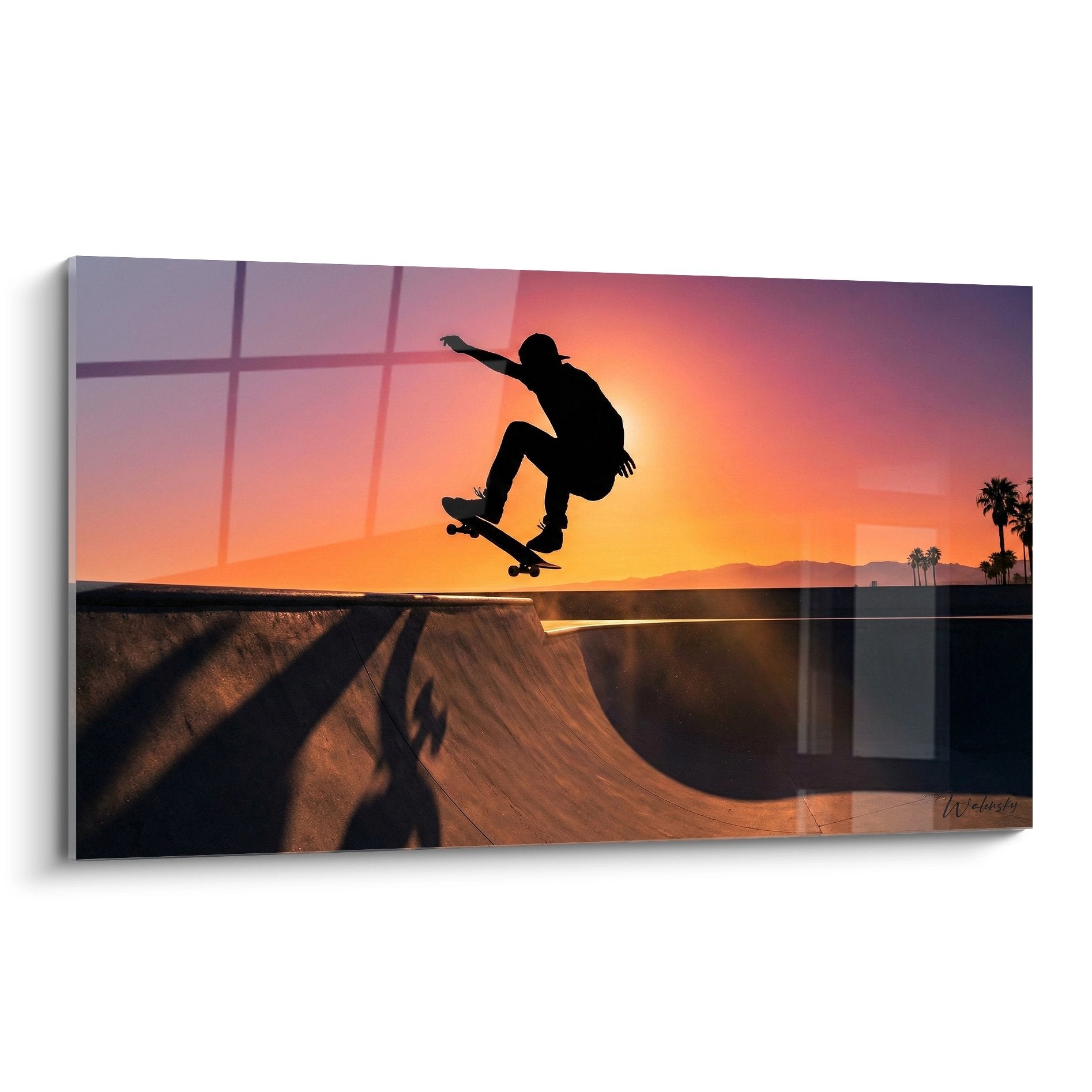 Wandbild zeigt Skateboarder Silhouette springend über Halfpipe bei orangenem Sonnenuntergang mit Palmen