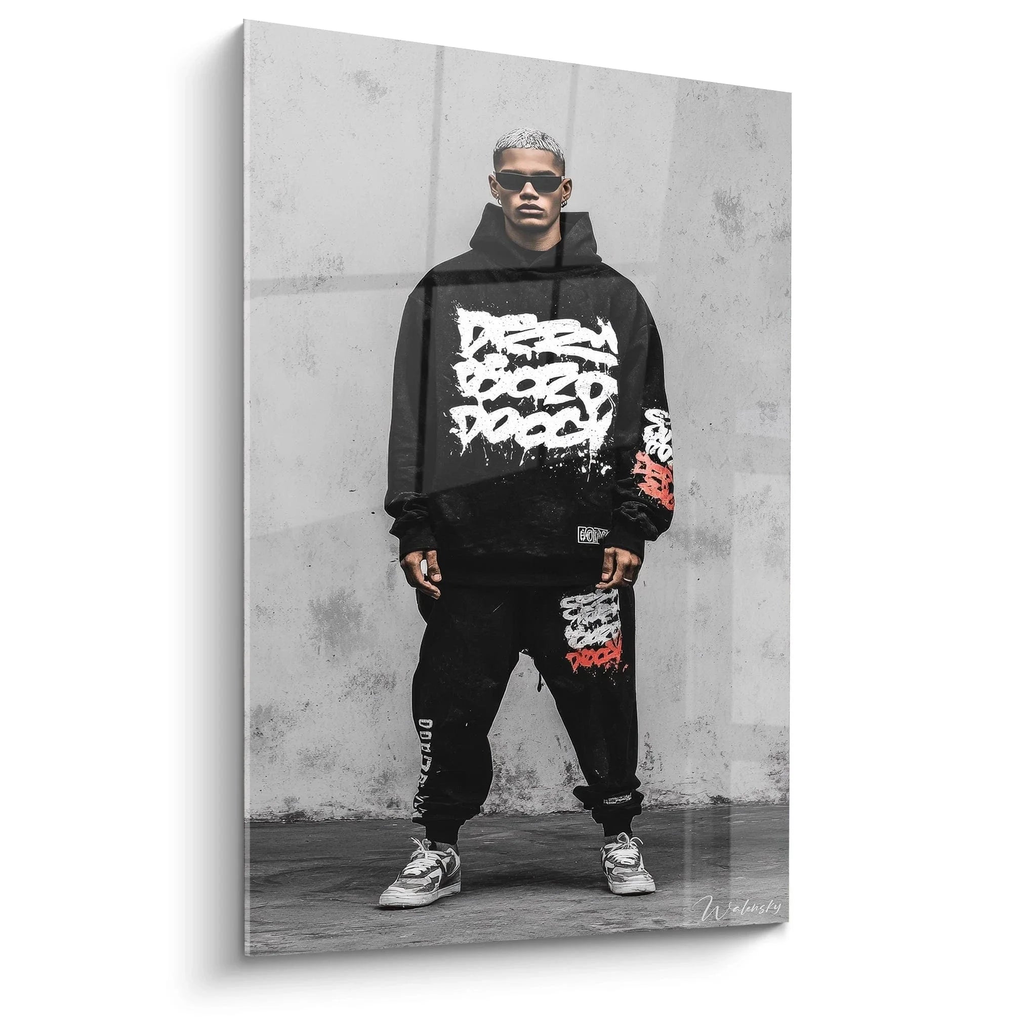 Wandbild Streetwear Model in schwarzem Hoodie mit Graffiti-Prints vor Betonwand - Urban Fashion Style